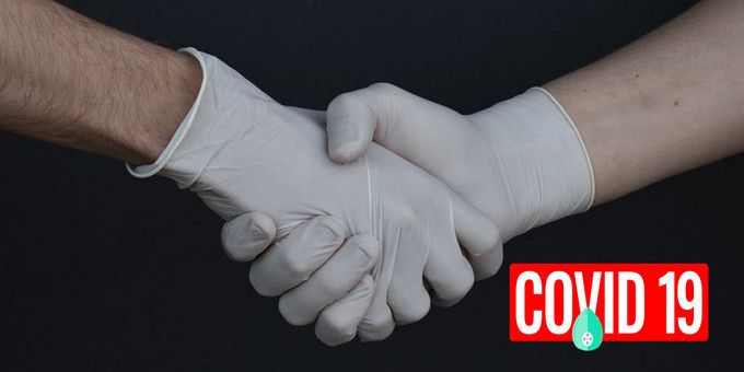 COVID-19 Pandemic Bang On Auto Industry depicted by two gloves wearing hands shaken