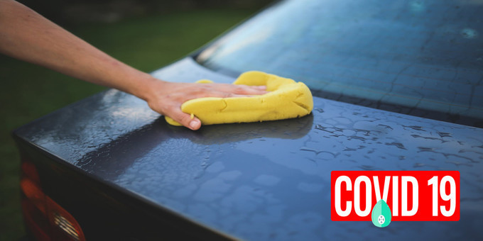 a black wet car extended back being cleaned by yellow sponge